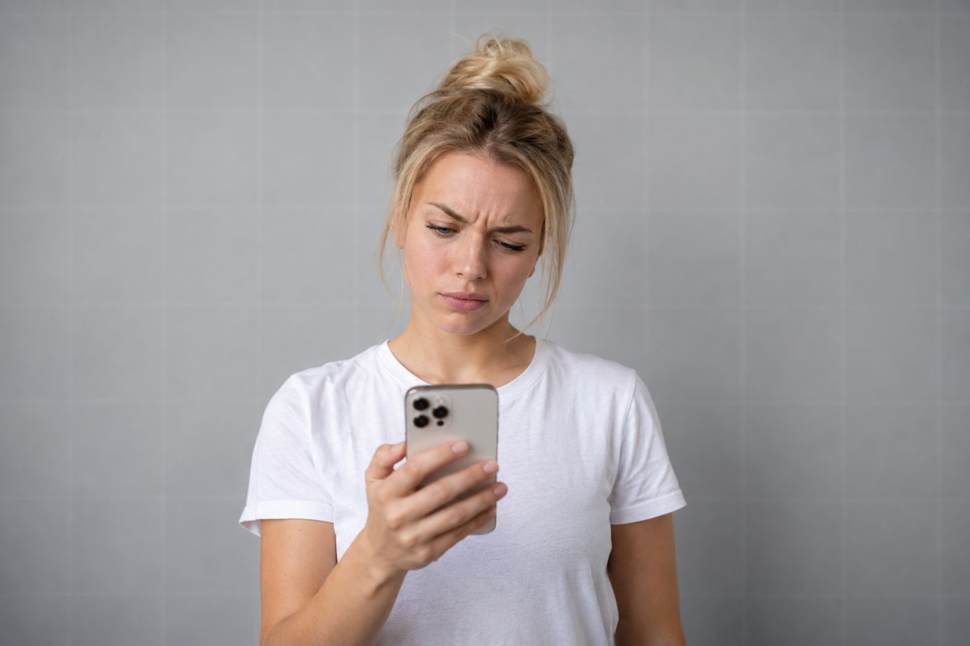 Puzzled young woman raising an eyebrow at her iPhone